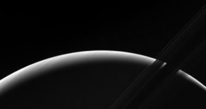NASA's Cassini spacecraft peers toward a sliver of Saturn's sunlit atmosphere while the icy rings stretch across the foreground as a dark band.(NASA)